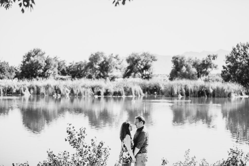 A black and white wide shot of a couple posing near a pond at Floyd Lamb Park in Las Vegas.