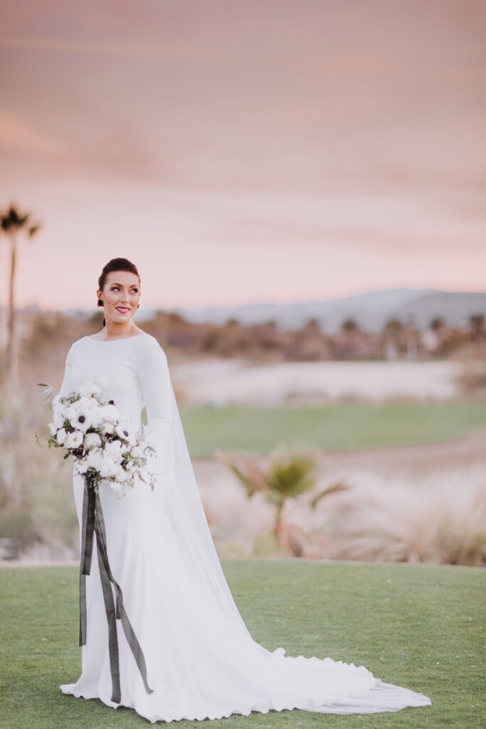 A bride stands on a golf green while holding her bouquet at Red Rock Country Club in Las Vegas.