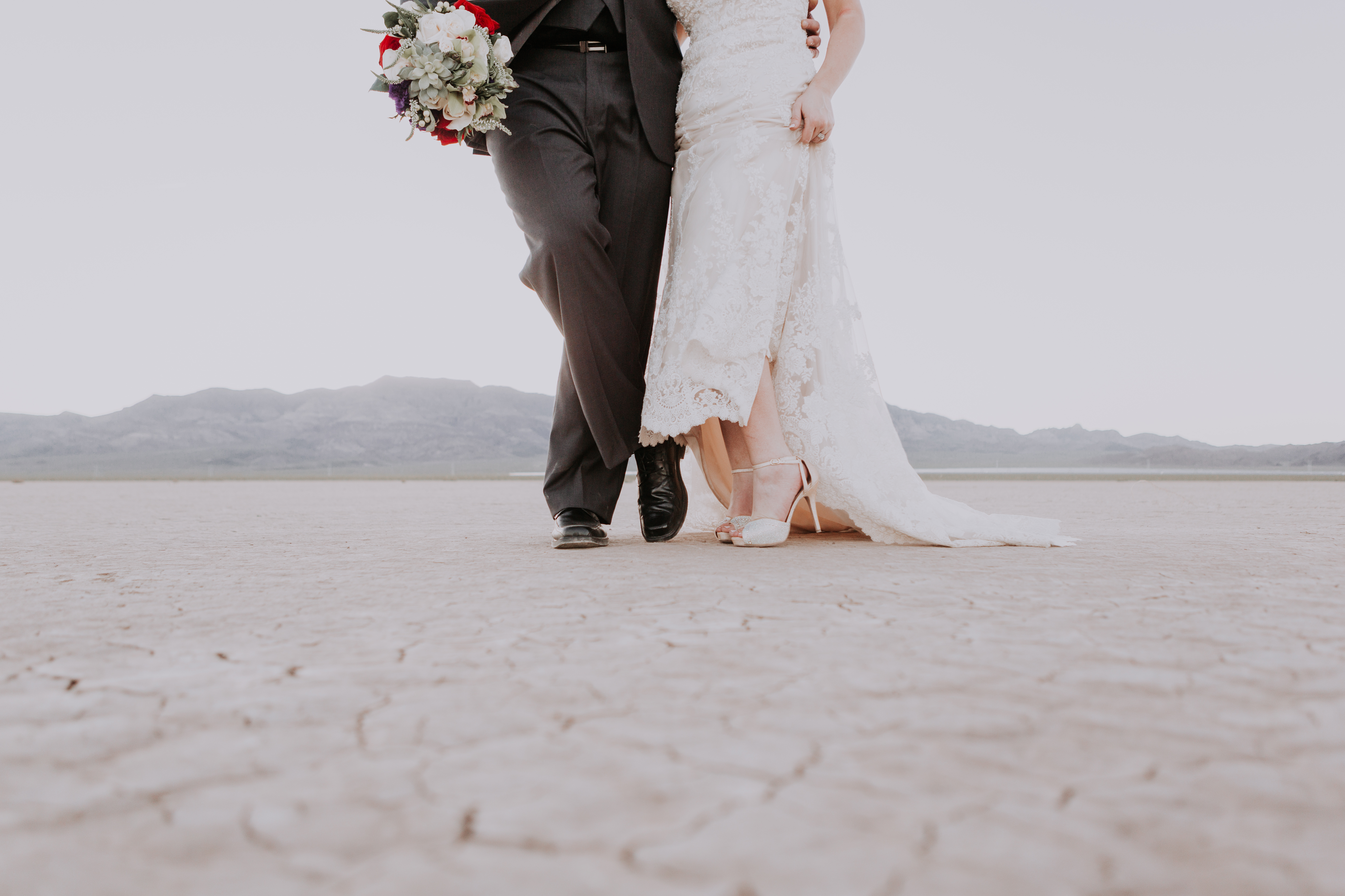 bride and groom shoe off their shoes in the desert
