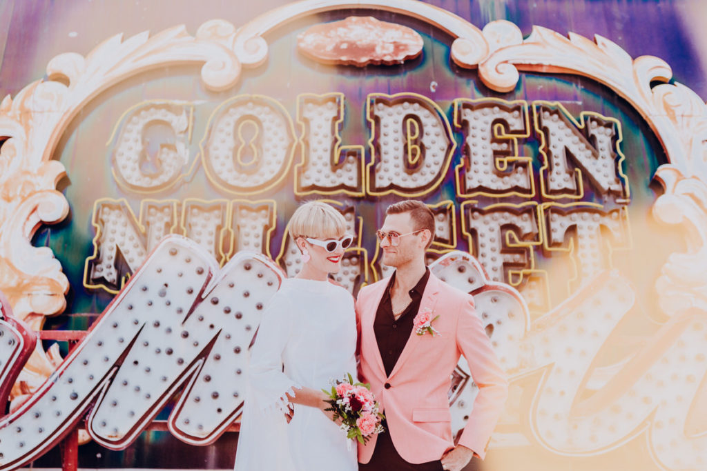 neon museum wedding pictures bride and groom laughing in front of golden nugget