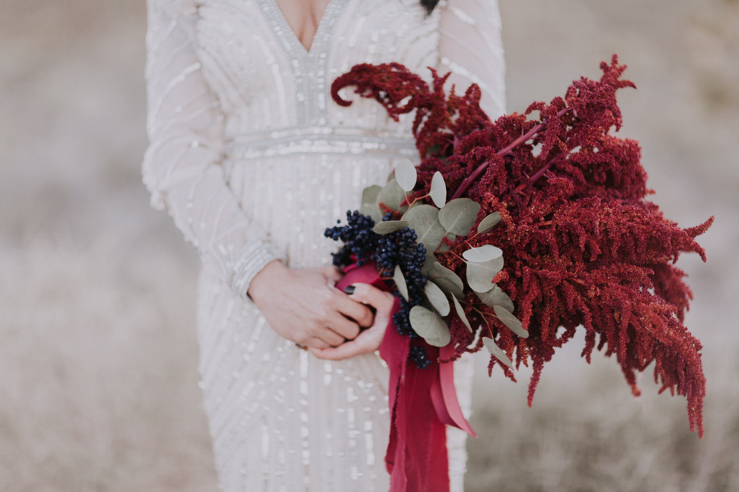 bride holds burgandy bouquet accented with soft green eucalyptus leaves.