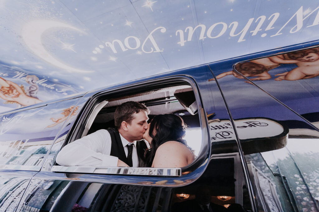 A couple kiss as they are pronounced "husband and wife" in the backseat of a limousine parked in a drive-thru wedding chapel.