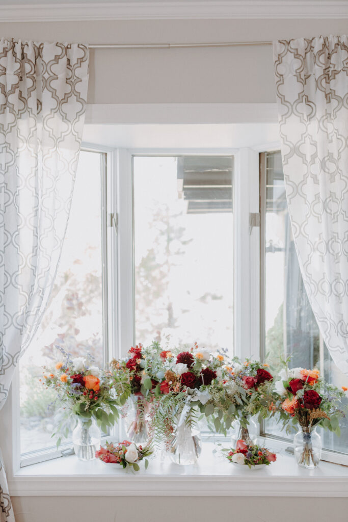 A bay window inside one of the wedding suites with bouquets sitting on the window ledge.