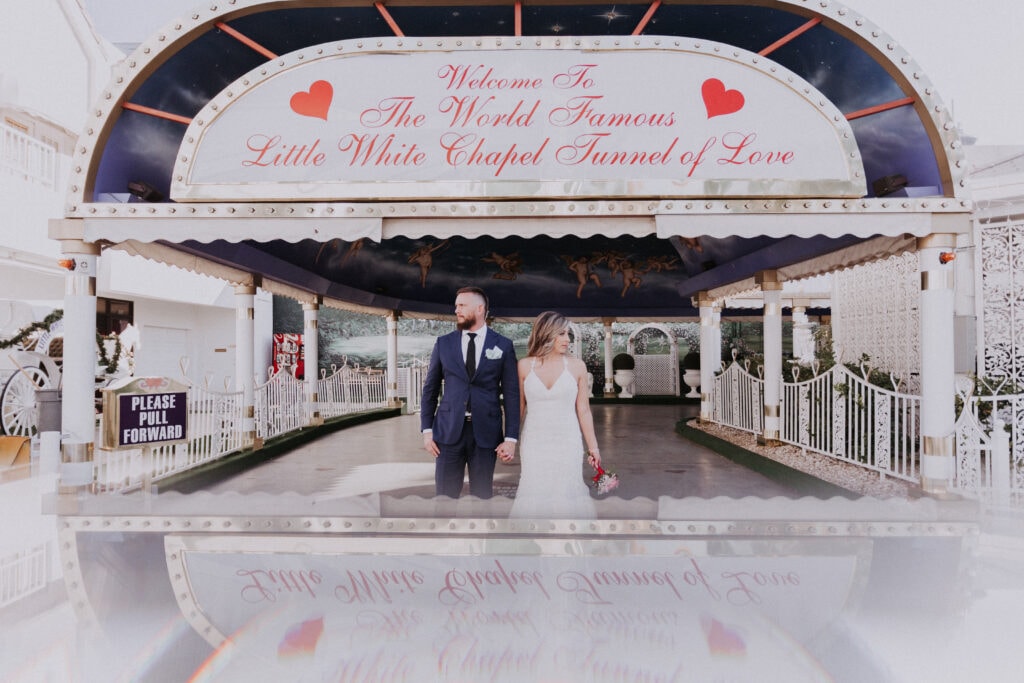 A Bride and Groom stand hand-and-hand, under the awning of the Tunnel of Love at A Little White Wedding Chapel in Las Vegas.