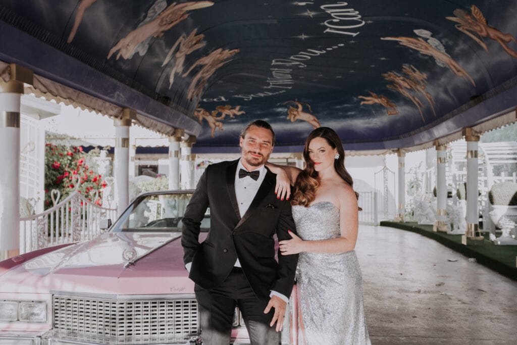 A couple poses against a pink Cadillac after being wed in the Tunnel of Love at A Little White Wedding Chapel in Las Vegas.