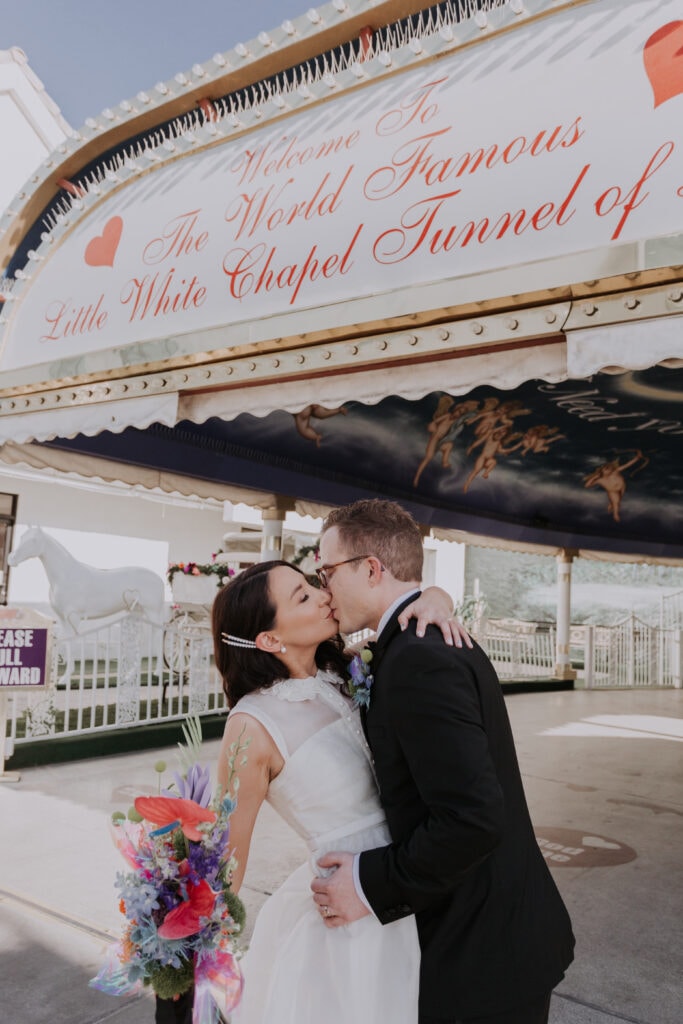 A couple kisses under the awning of the drive-thru Tunnel of Love at A Little White Wedding Chapel in Las Vegas.