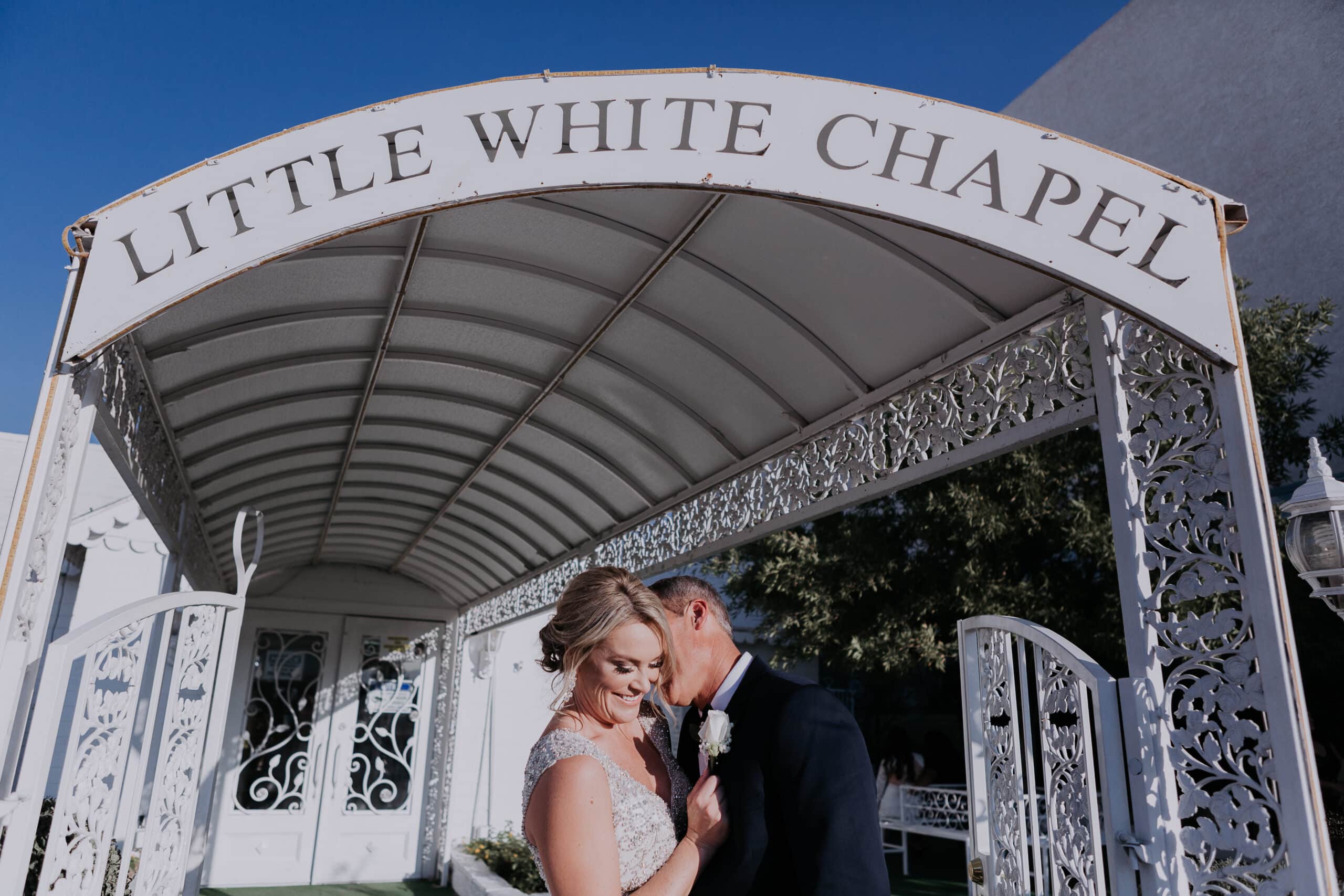 A Groom kisses his bride under the awning of the entrance to A Little White Wedding Chapel in Las Vegas.